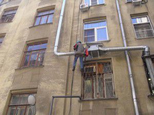 альпинист монтирует вентиляционную установку снаружи здания